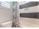 Stylish bathroom features striped tiled walls, shower and tub, and a modern shower curtain at 25751 S 227Th Way, Queen Creek, AZ 85142