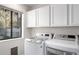 Bright laundry room features a washer, dryer, white cabinets, and a window at 3019 E Redfield Rd, Phoenix, AZ 85032