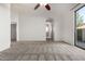 A large, carpeted bedroom with a ceiling fan and a view into the bathroom at 3019 E Redfield Rd, Phoenix, AZ 85032