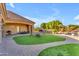 A beautiful outdoor living space with a built-in stone fireplace, grill, synthetic grass, and a seating area at 3446 E Knoll St, Mesa, AZ 85213