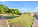 Wide grassy backyard featuring mature trees and a view of outdoor kitchen area, providing ample space for outdoor activities at 3446 E Knoll St, Mesa, AZ 85213