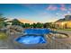 Inviting pool and spa area with rock accents, lush landscaping, and evening lighting for a serene ambiance at 3446 E Knoll St, Mesa, AZ 85213