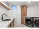 Well-lit laundry room featuring modern appliances, cabinetry, a window, stylish tile floor, and countertop space at 39877 N 107Th Way, Scottsdale, AZ 85262