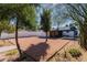 Spacious backyard featuring gravel landscaping, mature trees, and a covered patio area at 406 W Coolidge St, Phoenix, AZ 85013