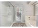 Bathroom with a glass door shower and a tub, accented by wood-look flooring and access to the exterior at 42313 W Sparks Dr, Maricopa, AZ 85138