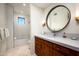 Chic bathroom with a herringbone-tiled shower, a circular mirror, and a wood vanity with marble countertops at 42690 N 98Th Pl, Scottsdale, AZ 85262