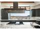 An oversized stainless vent hood hangs over a marble cook top with a scenic desert landscape at 42690 N 98Th Pl, Scottsdale, AZ 85262
