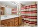 Bathroom with double sink vanity and warm-toned tile, featuring a colorful striped shower curtain at 4769 E Thunderheart Trl # 101, Gilbert, AZ 85297