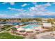 Aerial view of community pool with ample seating, umbrellas, and a lake in the background at 4769 E Thunderheart Trl # 101, Gilbert, AZ 85297