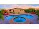 Beautiful backyard pool and spa with red lounge chairs and desert landscaping at sunset at 6044 E Hodges St, Cave Creek, AZ 85331