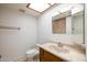 Functional bathroom with a white toilet, vanity with a mirror and a skylight for natural light at 6409 W Riviera Dr, Glendale, AZ 85304