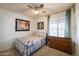 A quaint bedroom featuring a decorative quilt bed and a wooden dresser at 6409 W Riviera Dr, Glendale, AZ 85304