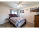 Cozy bedroom with a wooden headboard bed frame, ceiling fan, and two decorative wall hangings at 6409 W Riviera Dr, Glendale, AZ 85304