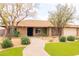 Charming single-story brick home features well-manicured landscaping, mature trees, and a welcoming walkway at 6409 W Riviera Dr, Glendale, AZ 85304