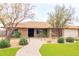 Charming single-story brick home features well-manicured landscaping, mature trees, and a welcoming walkway at 6409 W Riviera Dr, Glendale, AZ 85304