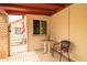 Cozy covered porch with a small table, chair, and open gate, leading to an outdoor seating area at 6409 W Riviera Dr, Glendale, AZ 85304