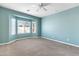 Large bedroom features a bay window, ceiling fan, carpet flooring, and pastel blue walls at 6792 W Willow Way, Florence, AZ 85132