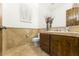 Charming bathroom with travertine tile, wood cabinet, and natural light from window with shutters at 7603 E Soaring Eagle Way, Scottsdale, AZ 85266