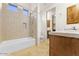 Bathroom with a tub and shower combo, tile surround, and wood cabinets at 7603 E Soaring Eagle Way, Scottsdale, AZ 85266