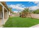 View of the backyard with a wood playset, artificial grass and mature palm tree at 7605 W Avalon Dr, Phoenix, AZ 85033