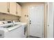 Bright laundry room features cabinets above the washer and dryer, along with an exterior door at 7605 W Avalon Dr, Phoenix, AZ 85033