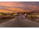 View of an illuminated driveway leading to a luxurious property with mountain views at sunset at 9780 E Baseline Ave, Gold Canyon, AZ 85118