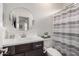 Elegant bathroom with a modern vanity, round mirror, patterned wallpaper, and shower with curtain at 10657 E Texas Ave, Mesa, AZ 85212