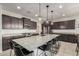 Gourmet kitchen boasts an oversized center island, sleek black stools, stainless steel appliances, and granite countertops at 10657 E Texas Ave, Mesa, AZ 85212