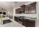 Modern kitchen with stainless steel appliances, granite countertops, dark wood cabinets, and view into the living room at 10657 E Texas Ave, Mesa, AZ 85212