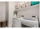 Bright laundry room includes modern washer and dryer units with shelving and storage basket at 10657 E Texas Ave, Mesa, AZ 85212