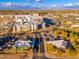 An aerial view displays modern apartments and commercial buildings with street and parking access under blue skies at 12212 N Paradise Vlg S Pkwy # 129, Phoenix, AZ 85032