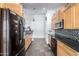 Galley style Kitchen with maple cabinetry, black appliances, and tile backsplash and flooring at 1344 W Seascape Dr, Gilbert, AZ 85233