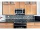Modern kitchen features stainless steel microwave, granite counters, mosaic backsplash, and light wood cabinets at 1344 W Seascape Dr, Gilbert, AZ 85233