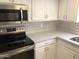 Bright kitchen features stainless steel microwave, white cabinetry, quartz countertops, and a decorative tile backsplash at 15402 N 28Th St # 112, Phoenix, AZ 85032