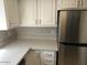 Modern kitchen features stainless steel refrigerator, white cabinetry, and a stylish circular tile backsplash at 15402 N 28Th St # 112, Phoenix, AZ 85032