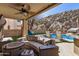 Inviting covered patio with stylish seating and outdoor kitchen, overlooking a pool and picturesque rock wall backdrop at 16834 S 20Th Pl, Phoenix, AZ 85048