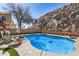 Sparkling pool with a manicured lawn and a rock wall backdrop, creating a private and serene outdoor oasis at 16834 S 20Th Pl, Phoenix, AZ 85048