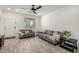 Bright living room featuring modern light gray couches, wood-look tile flooring, and a ceiling fan at 16888 W Alice Ave, Waddell, AZ 85355