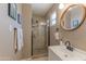 Modern bathroom showcasing a glass-enclosed shower with tiled walls and floor, and a round mirror at 1749 E Medlock Dr, Phoenix, AZ 85016