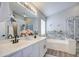 Bright bathroom featuring double sinks, decorative backsplash, a soaking tub, and a glass enclosed shower at 17526 W Coyote Trail Dr, Goodyear, AZ 85338