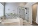 Spa-like bathroom featuring a soaking tub and glass-enclosed shower with decorative tile accents at 17526 W Coyote Trail Dr, Goodyear, AZ 85338
