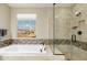 Elegant bathroom with tiled tub, separate shower, and a large window offering natural light and scenic views at 18519 N 94Th St, Scottsdale, AZ 85255
