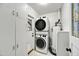 Functional laundry room equipped with a stacked washer and dryer, white cabinets, and a window at 2045 W Orange Dr, Phoenix, AZ 85015