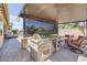 Outdoor kitchen featuring built-in grill, counter space, and seating under a covered patio with shades at 20520 E Mockingbird Dr, Queen Creek, AZ 85142
