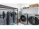 Bright laundry room with modern washer and dryer, shelving, and ample storage space for convenience at 21090 E Camina Buena Vis, Queen Creek, AZ 85142