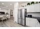 Kitchen area with stainless steel refrigerator, white cabinets, gray subway tiles and adjacent dining area at 21901 N Sonora Ln, Sun City West, AZ 85375