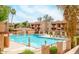A community pool with lounge chairs and an umbrella, surrounded by lush landscaping and multi-story buildings at 3031 N Civic Center Plz # 205, Scottsdale, AZ 85251