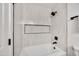 A clean, white bathroom features a bathtub and shower combination with sleek, neutral tiling and modern fixtures at 3037 E Pueblo Ave, Mesa, AZ 85204