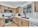 Well-equipped kitchen with modern stainless steel appliances, wood cabinetry, white countertops, and natural light at 3037 E Pueblo Ave, Mesa, AZ 85204