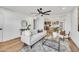 Open living room featuring a comfortable sofa, modern decor, a ceiling fan, and wood floors with an adjacent kitchen at 3037 E Pueblo Ave, Mesa, AZ 85204